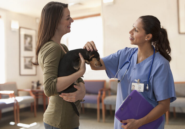 Female veterinarian talking with dog owner female-veterinarian-talking-with-dog-owner